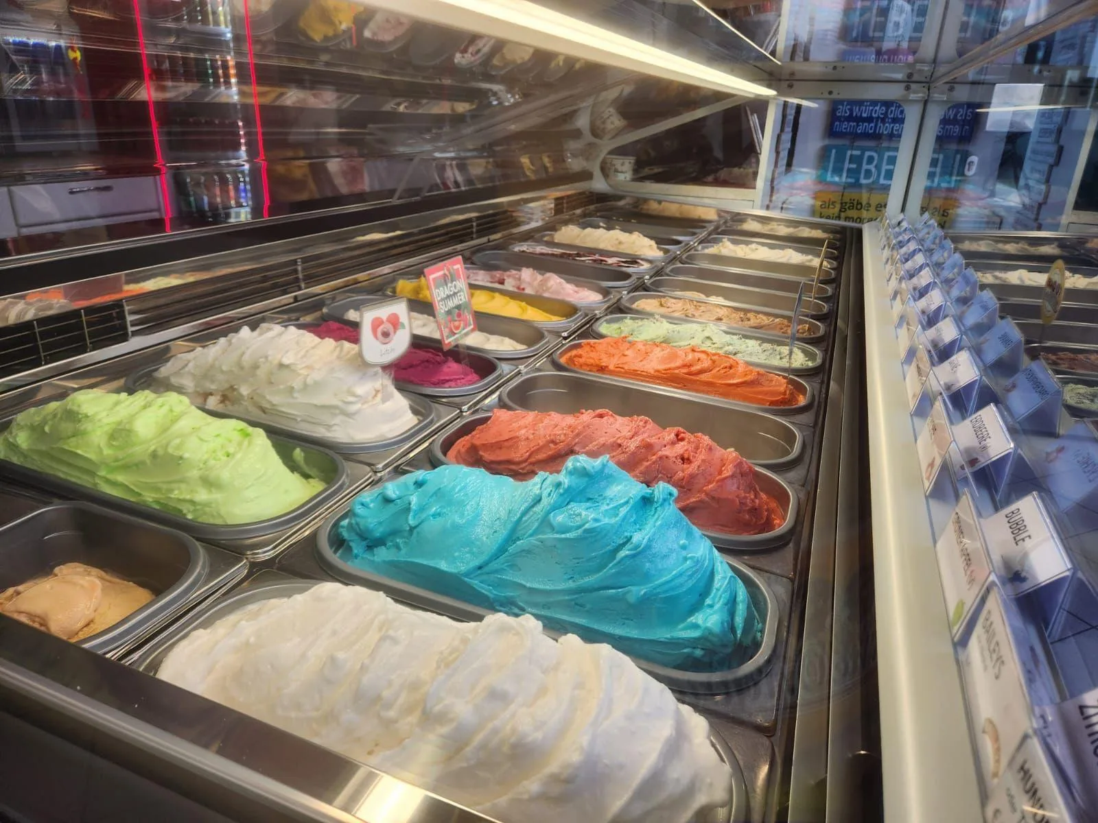 Eistheke der Eismacherei mit vielen bunten, frisch aufgeschlagenen Eissorten