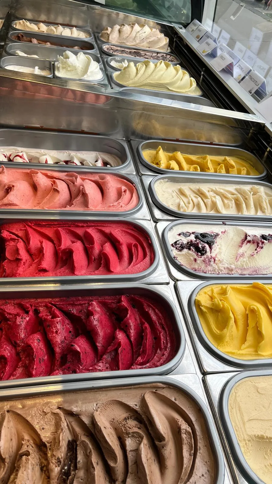 Nahaufnahme cremiger Eissorten in der Vitrine – von Frucht bis Schokolade